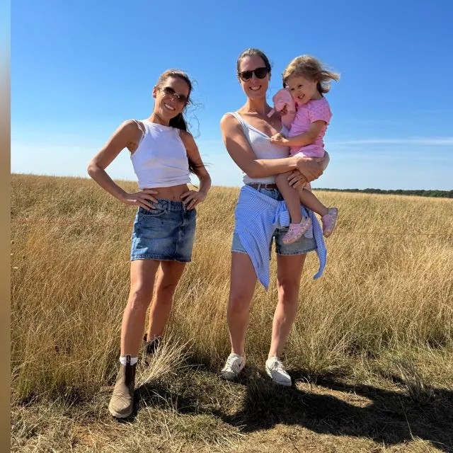 Jersey Belle founders, two mums with a young daughter, standing in a sunlit Welsh meadow
