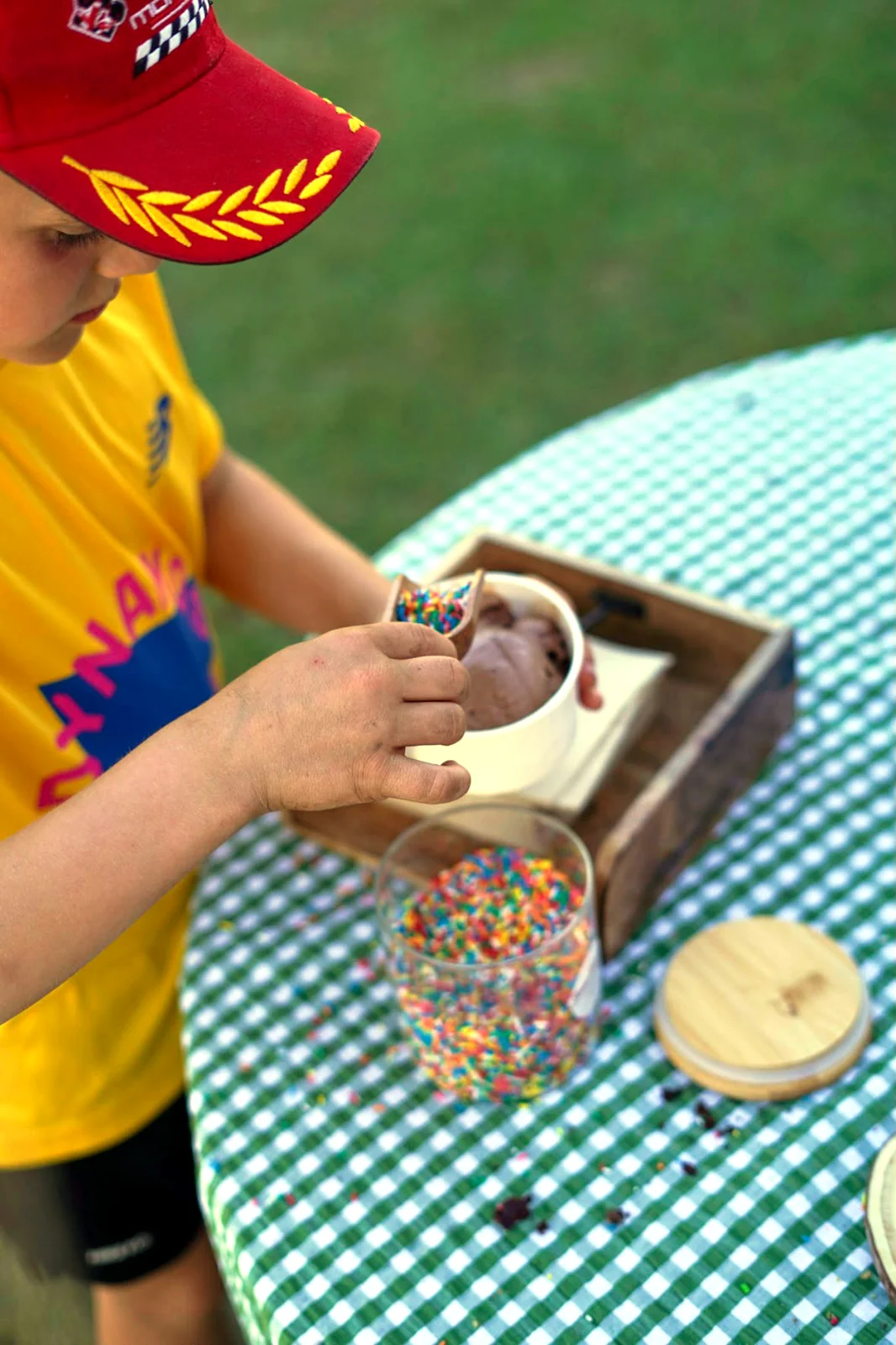 A child loading rainbow sprinkles onto a pot of chocolate ice cream at the DIY Sprinkle Station