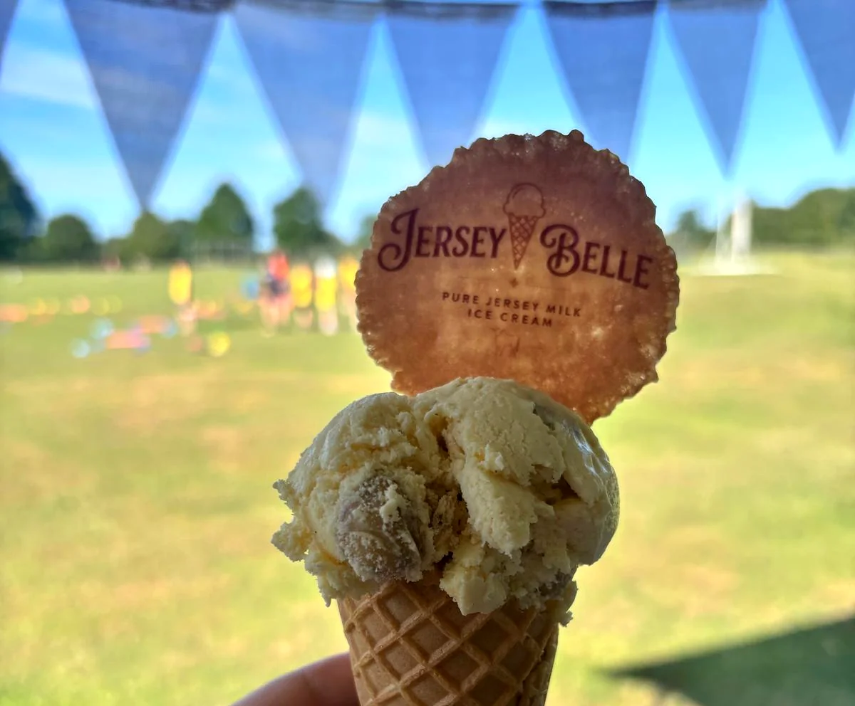 A scoop of Jersey Belle ice cream in a waffle cone topped with a branded wafer disc